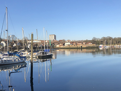 Sailing boats moored on the water, with Fareham town in the distance